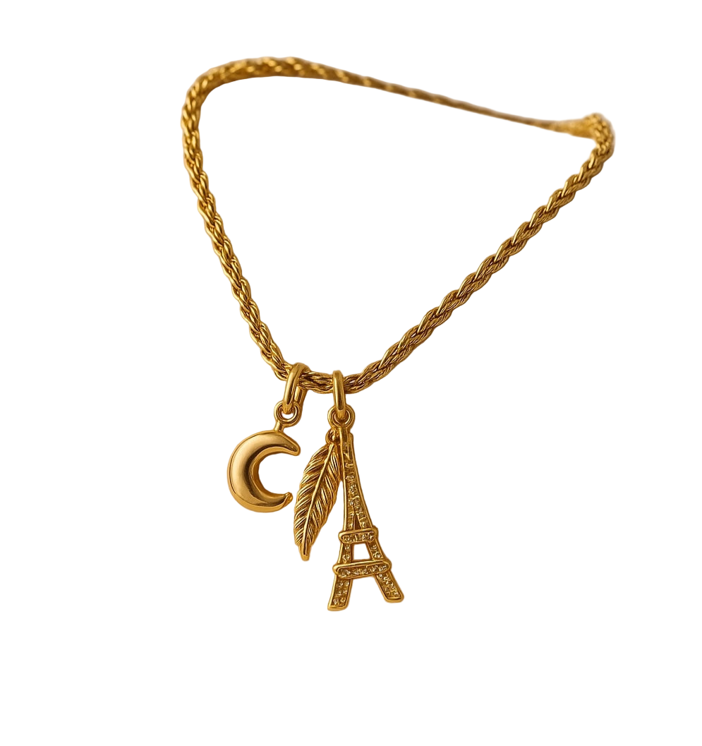 Gold necklace with Eiffel Tower charm on a beige jewelry box